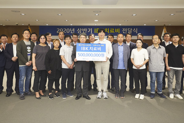 ▲8일 을지로 기업은행 본점에서 윤종원 은행장(왼쪽 열한 번째)과 중소기업 근로자 가족들이 치료비 전달식을 마치고 기념촬영을 하고 있는 모습.