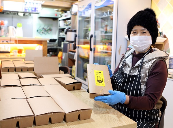 남촌상인회 윤남순 회장이 명동밥집에 보낼 도시락을 포장하고 있다.