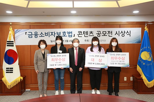 ▲ 윤석헌 금융감독원장과 김은경 금융소비자보호처장이 수상자들과 함께 사진을 찍고 있다. 왼쪽부터 김은경 금융소비자보호처장, 최우수상 수상자, 윤석헌 금융감독원장, 대상 수상자, 최우수상 수상자