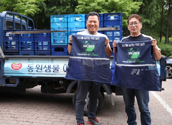▲동원샘물 대리점 직원들이 폐페트병으로 만들어진 친환경 유니폼을 들고 기념 사진을 촬영하고 있다