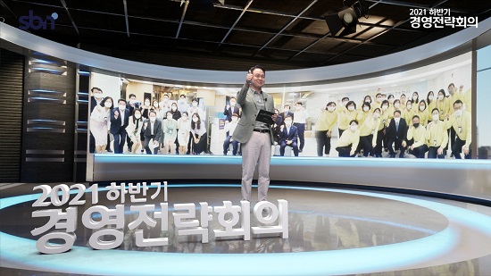 ▲ 지난 16일 신한은행 사내 방송국 가상스튜디오의 디지털 사내방송을 통해 진행된 ‘2021 하반기 경영전략회의’에서 진옥동 은행장이 상반기 고생한 직원들에게 격려의 메세지를 전하는 모습