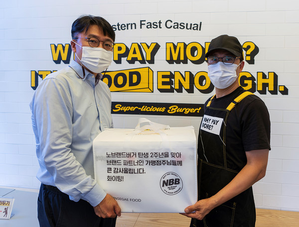 ▲경기 성남시 수정구 노브랜드 버거 성남태평점에서 신세계푸드 안수형 NBB팀장(왼쪽)이 정재호 가맹점주에게 보양식 세트를 전달하고 있다
