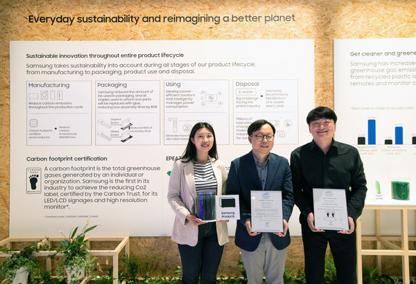 ▲ISE 2022가 열리고 있는 스페인 바르셀로나 피라 그라 비아 전시장에서 삼성전자 영상디스플레이사업부 Enterprise 개발 이종포 상무(가운데)와 개발자들이 사이니지 제품 탄소 발자국 인증서와 제품에 활용되는 재생 플라스틱을 들고 있다.