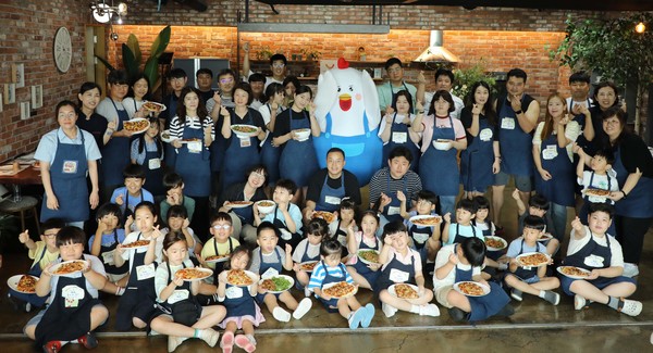 ▲피오봉사단 11기 임직원 및 소비자 가족이 쿠킹클래스에서 만든 치킨피자와 닭목살 덮밥을들고 기념촬영을 하고 있다