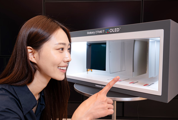 ▲삼성디스플레이 모델이 폴더블 패널 구조 전시용 박스를 살펴보고 있다.
